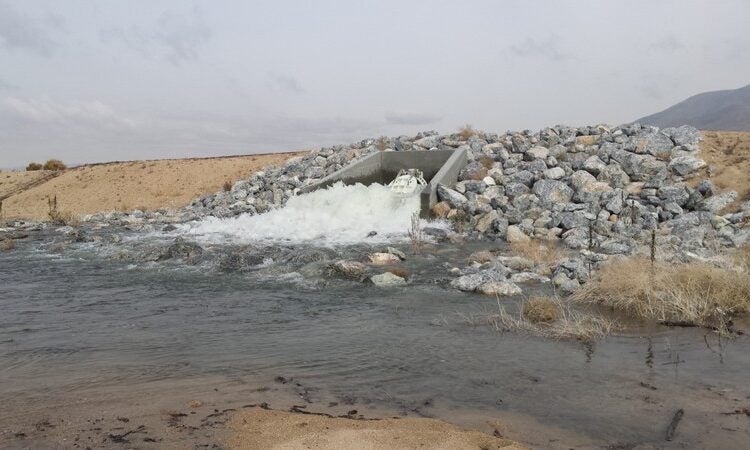 Water rushing from pipe outlet surrounded by rocks